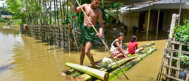 People-cross-a-flood-affected-area-on-a-makeshift-raft-after-heavy-rainfall-in-Golaghat-on-Wednesday.-PTI